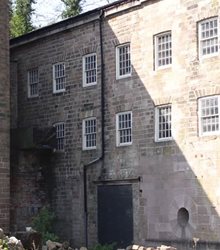 Colour photograph of an exterior wall at the Arkwright factory site, showing the location where the mill wheel used to sit.