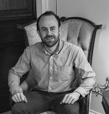 black and white photo of Jonathan Memel, seated.