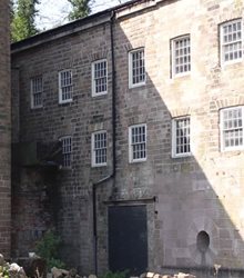 Colour photograph of an exterior wall at the Arkwright factory site, showing the location where the mill wheel used to sit.
