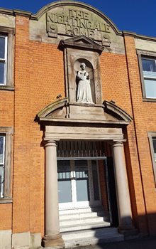 Colour photograph of the exterior of the Nightingale Home, Derby, featuring the sign and a statuette of Nightingale above a doorway.