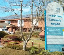 colour photo of the exterior of London Road hospital with its NHS sign.